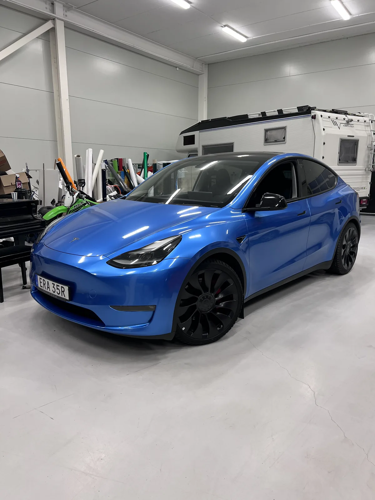 Blå Tesla med svarta fälgar och mörka detaljer.