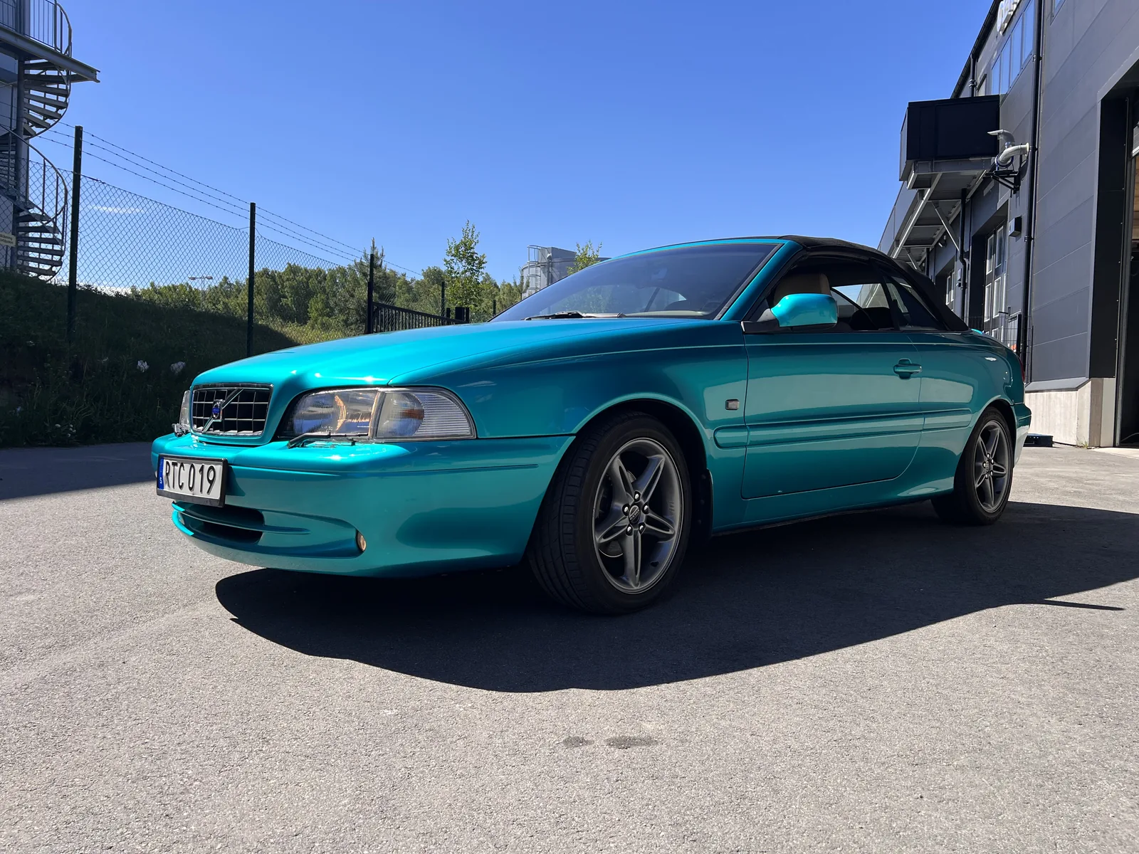 Turkos cabriolet fotograferad utanför verkstaden.