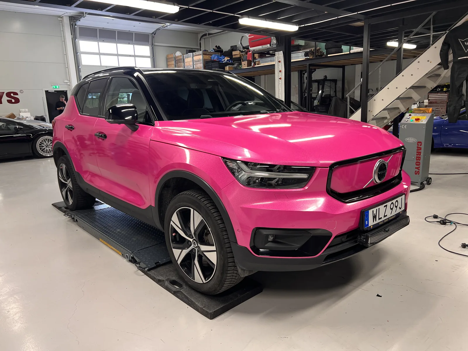 Rosa Volvo med svart tak och mörka kontrastdetaljer.