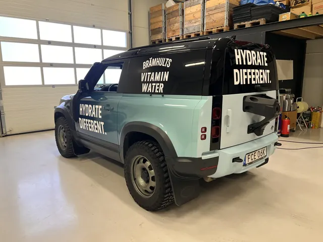 Tvåfärgad transportbil med Brämhults Vitamin Water-profilering.